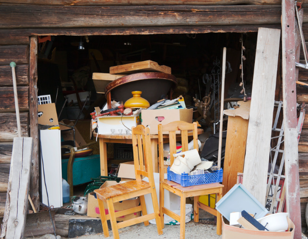 A shed containing stored furniture, boxes, chairs and household items