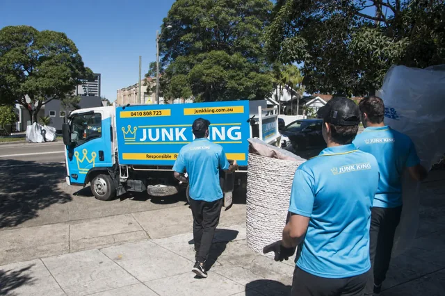 Junk King crew carrying bulky items beside the branded truck