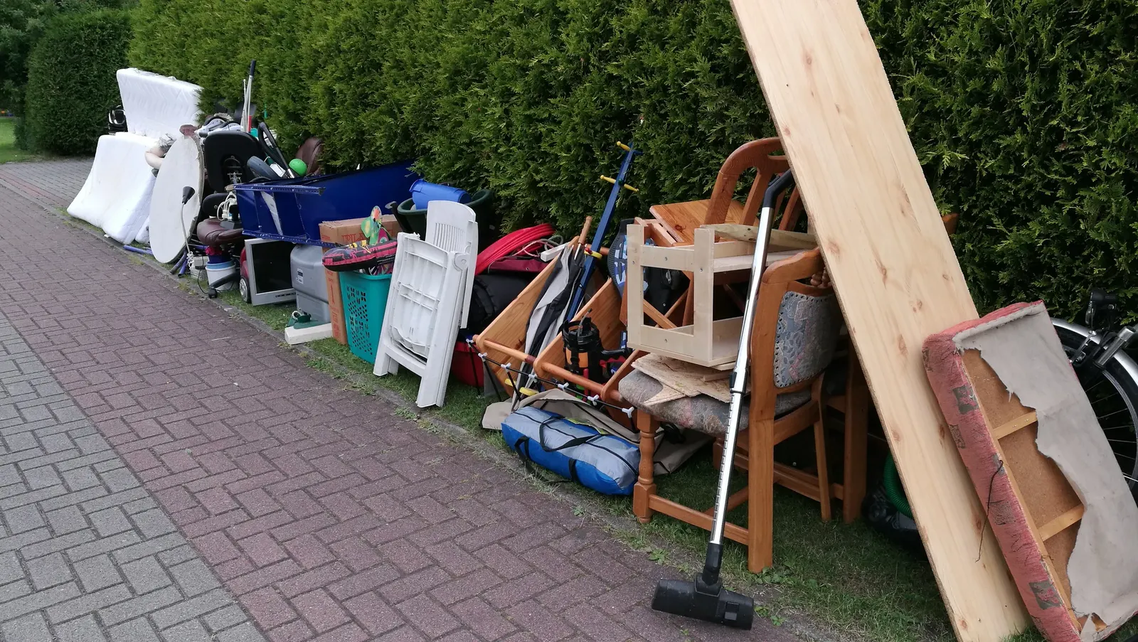 Mixed household rubbish lined up beside a driveway